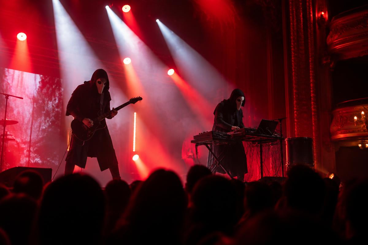 Performers silhouetted beneath violet stage lights